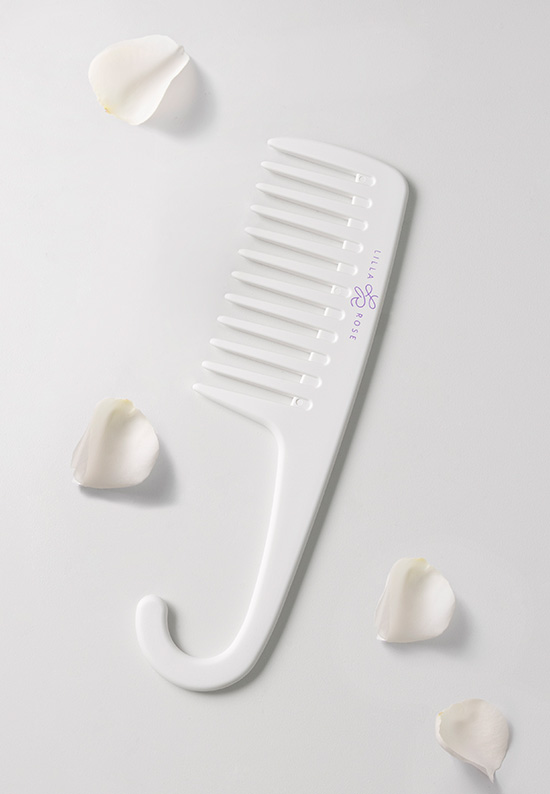 A Lilla Rose wide-tooth shower comb with a hook to hang it in the shower or from any angle. On an off-white background with four white flower petals surrounding it for the article The importance of taking care of your hair when you are stressed.. 