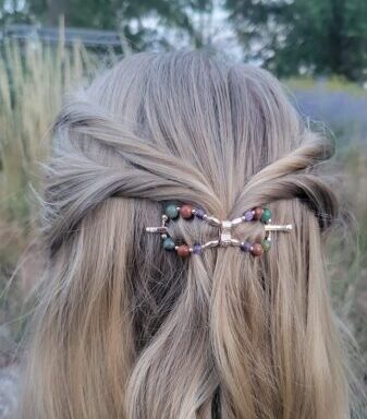 A young blonde lady with half up-hair style with twist coming into the middle from both sides being held together by a Lilla Rose Flexi Flip Hair Clip she is looking out into a field with tall light green grass with trees in the background for the article Get Your Hair Game On Point with Lilla Rose Accessories - Say Goodbye to Bad Hair Days!