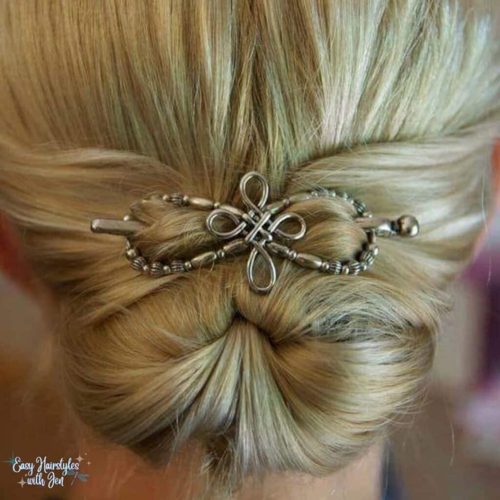 A woman with blonde hair in a bun secured with a Lilla Rose Flexi Clip with a Celtic Cross decoration on the Clip. The Clip is center right above the bun under the heading Lilla Rose Accessories-What are they for the article Get Your Hair Game On Point with Lilla Rose Accessories - Say Goodbye to Bad Hair Days!