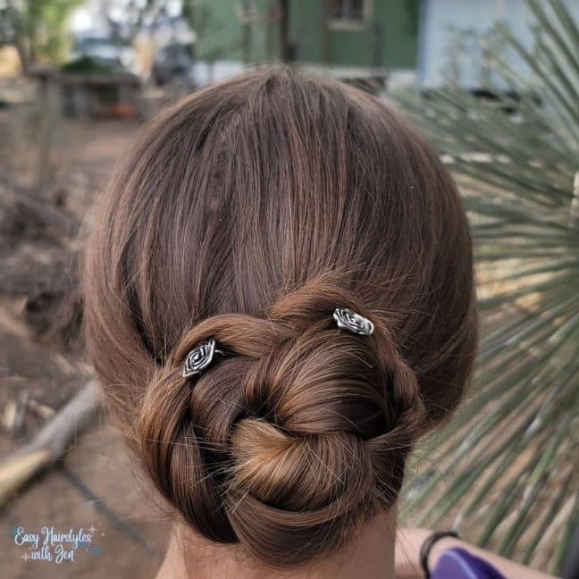 The back of a woman's head with her Hair in a bun secured with two Lilla Rose rose U-Pins for the article The role nutrition plays in hair health under the heading a brief history of Hair. 