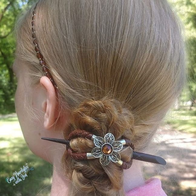 A young girl with a Lilla Rose hairband and her hair in a side bun secured with a Lilla Rose Flexi Eight and a hair stick. She is under the Article The role nutrition plays in hair health.